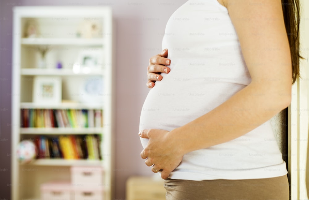 Close-up de mulher grávida irreconhecível com as mãos sobre a barriga
