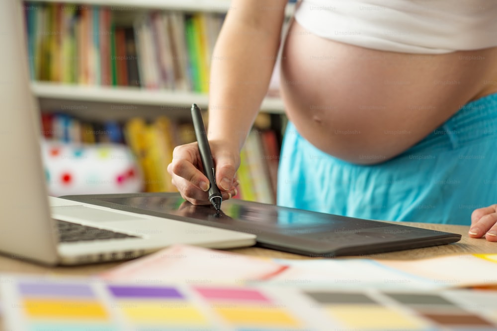 Donna incinta irriconoscibile nell'ufficio di casa con il computer portatile