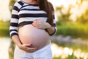Outdoor portrait of unrecognazable pregnant woman holding her belly