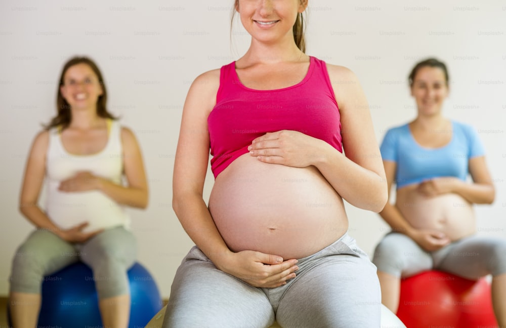 Young pregnant women doing exercise using a fitness ball