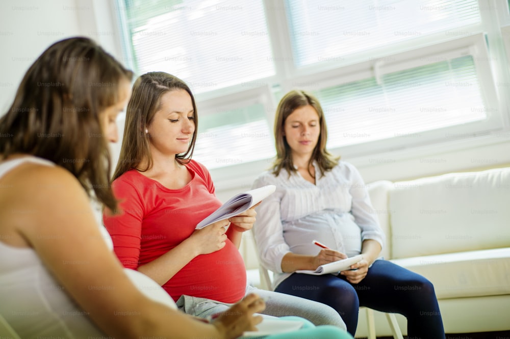 Mulheres grávidas felizes que se encontram na aula de pré-natal no hospital