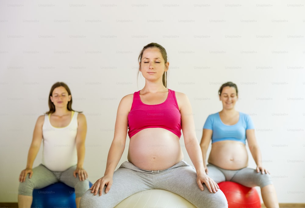 Young pregnant women doing exercise using a fitness ball
