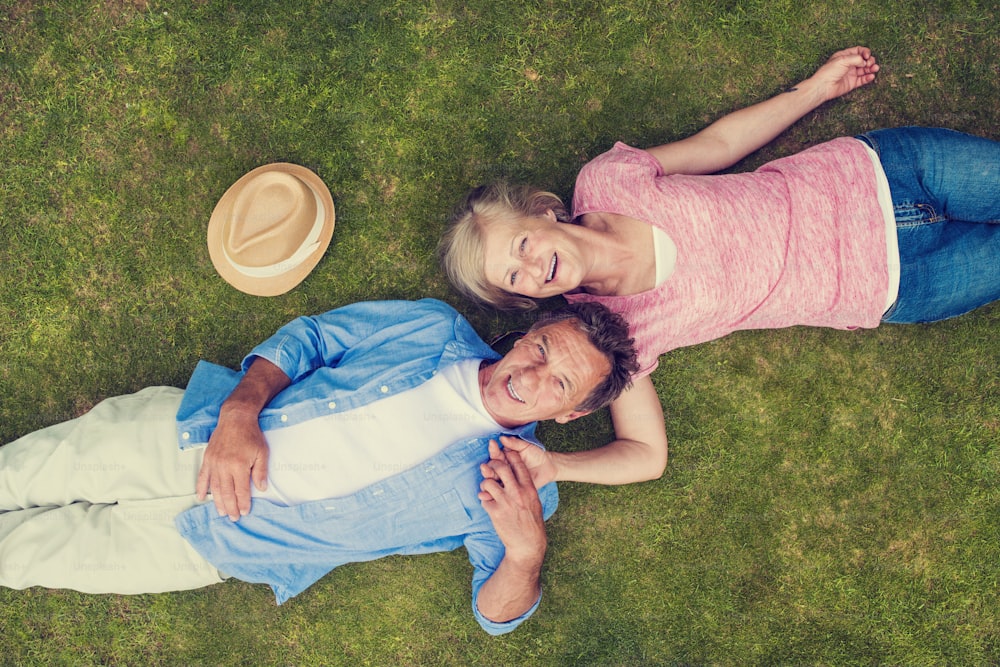 Beautiful seniors lying on a grass in a park hugging