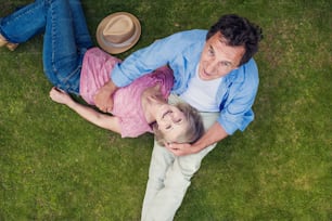 Beautiful seniors lying on a grass in a park hugging