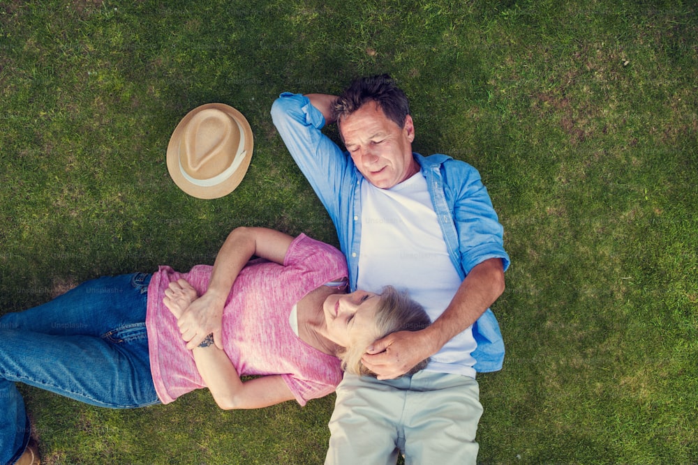 Beautiful seniors lying on a grass in a park hugging