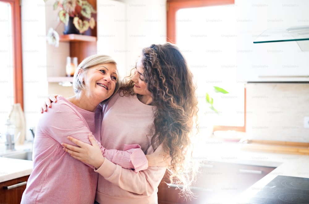 A teenage girl with mother or grandmother at home, hugging. Family and generations concept.