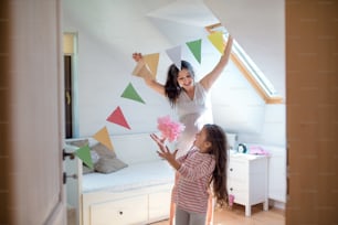 Porträt einer glücklichen schwangeren Frau mit kleiner Tochter drinnen zu Hause, Schlafzimmer dekorieren.