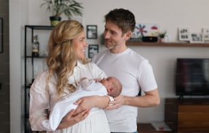 Uma mãe e um pai sorridentes segurando sua filha recém-nascida em casa