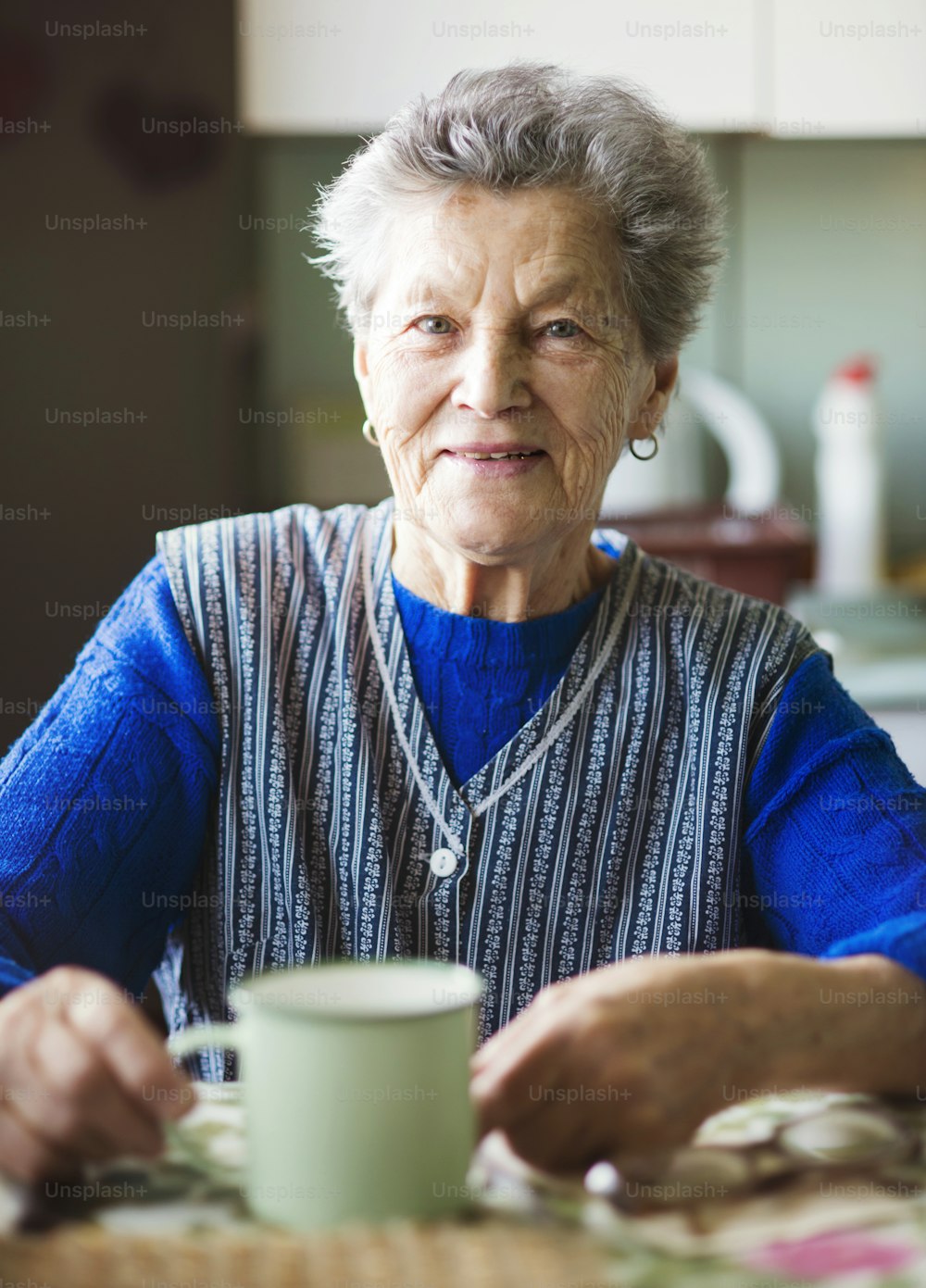 Alte Frau trinkt Tee in ihrer Küche im Landhausstil