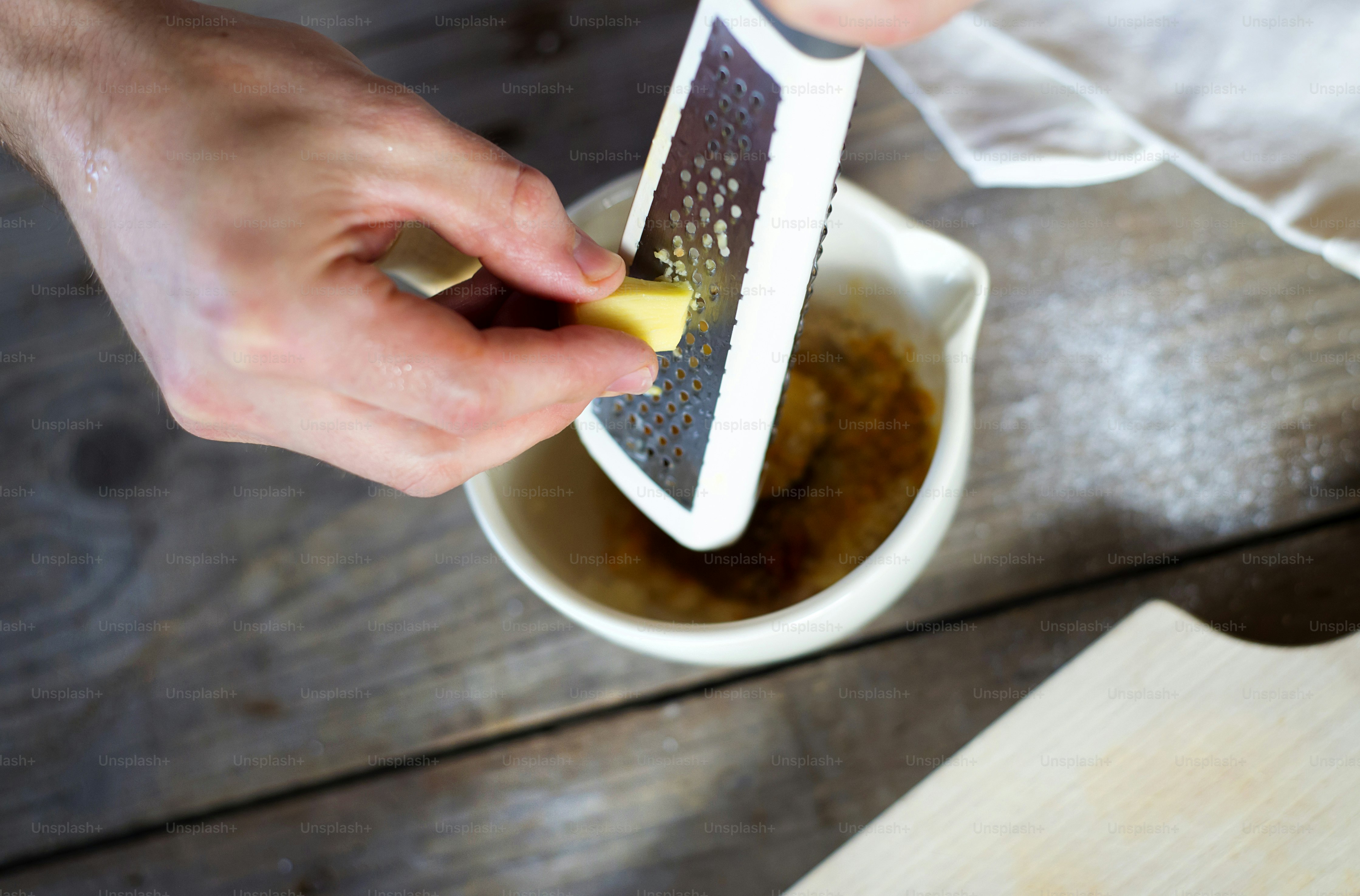 Hombre en la cocina rallando un trozo de jengibre
