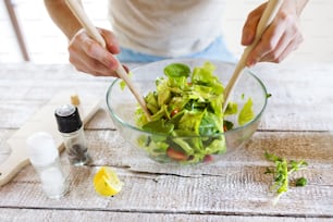 Homem irreconhecível na cozinha preparando salada de vegetais saudável