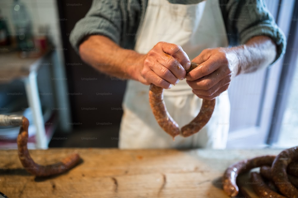 Hands of unrecognizable man making sausages the traditional way at home. Close up.