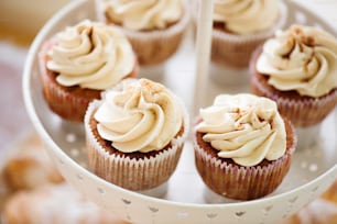 Aus nächster Nähe Cupcakes mit Vanillecreme im weißen Kuchenständer. Studioaufnahme.