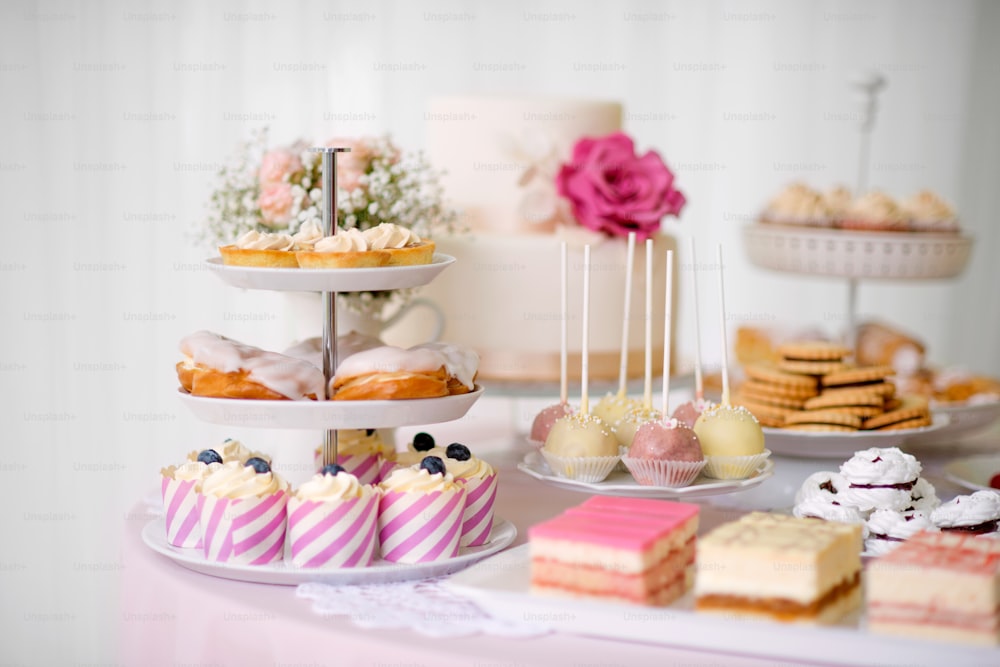 Mesa con un montón de pasteles, cupcakes, galletas y cakepops. Foto de estudio.