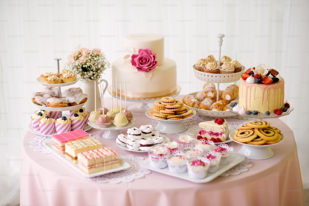 Table avec des charges de gâteaux, cupcakes, biscuits et cakepops. Prise de vue en studio.