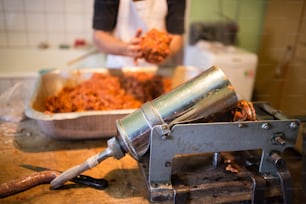 Unrecognizable man making sausages the traditional way at home. Holding meat ball in his hands, going to put it into sausage filler. Close up.