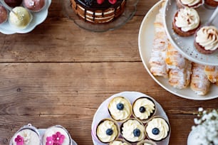 Table avec gâteau, cupcakes, cakepops et pâtisseries en corne. Photo studio sur fond en bois brun. Espace de copie. Pose plate.