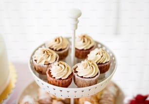 Aus nächster Nähe Cupcakes mit Vanillecreme im weißen Kuchenständer. Studioaufnahme.