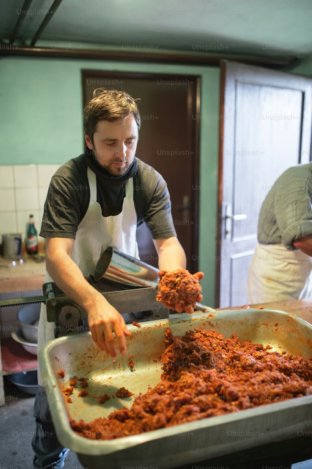 Dos hombres haciendo salchichas de la manera tradicional usando relleno de salchicha. Salchicha casera.