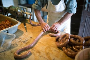 Unrecognizable man making sausages the traditional way using sausage filler. Homemade sausage.