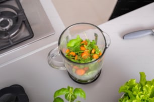 ブレンダーの準備ができている生のハーブと野菜は、新鮮な自家製スムージーを作ります。健康的なライフスタイルのコンセプト