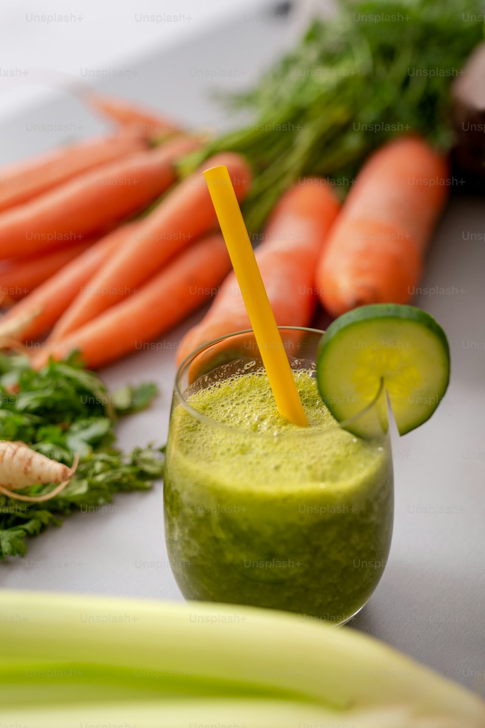 Un batido verde en vaso con pajita y pepino y verduras de fondo, desintoxicación, vegano, vegetariano bebida vegetal saludable