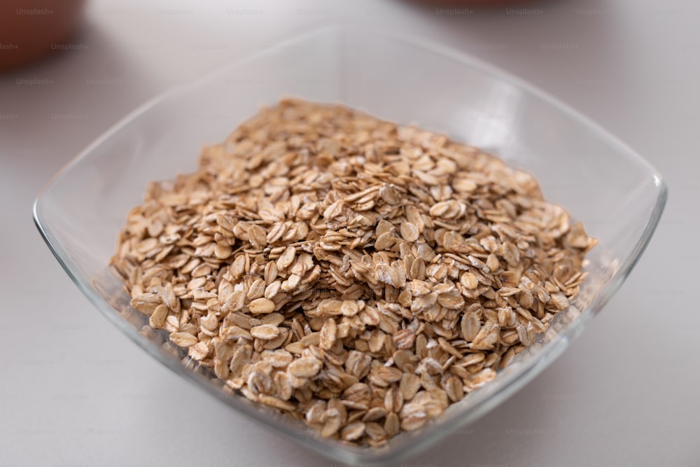 A glass bowl of oat flakes on white kitchen counter