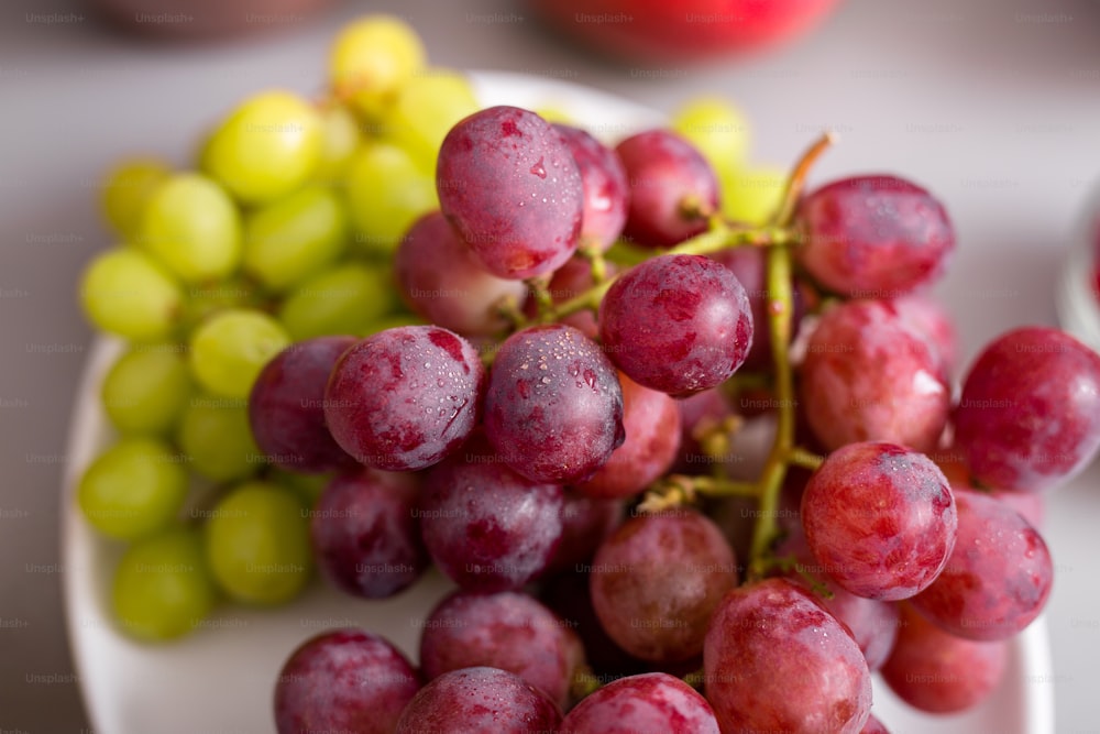 Raisin rouge et vert frais dans une assiette, gros plan. Concept de mode de vie sain.