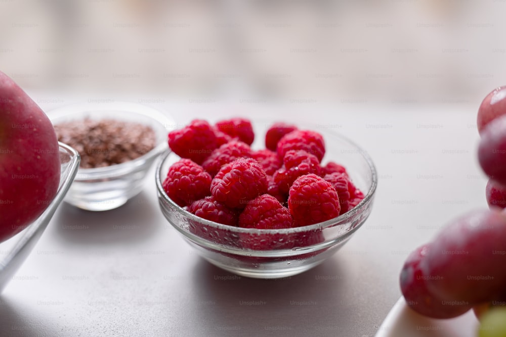 Fresh raspberries in a glass bowl on kitchen counter, healthy food for diet.