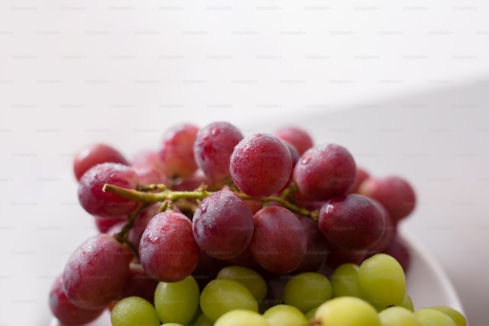Uva roja y verde fresca en un plato, primer plano. Concepto de estilo de vida saludable.
