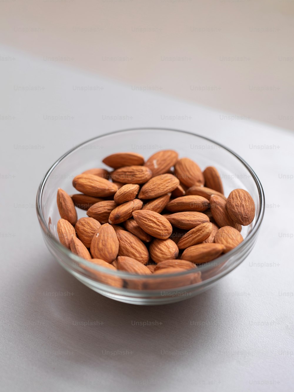 Almonds in a glass bowl on kitchen counter, healthy food for diet.
