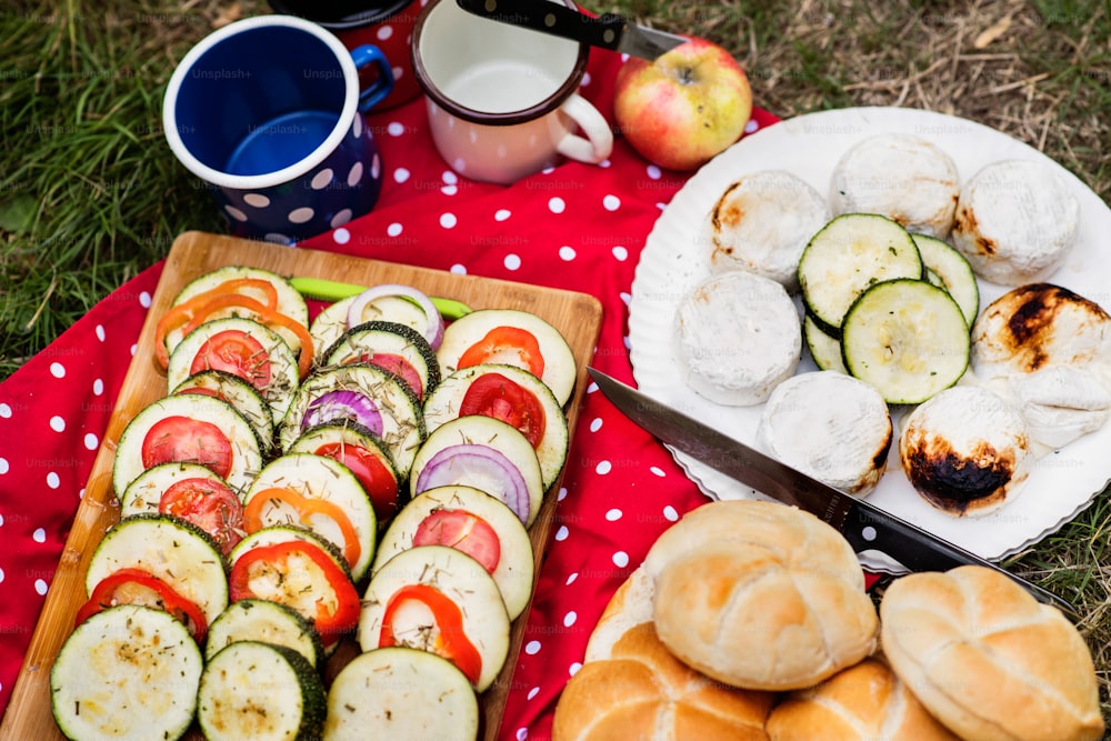 Grilled cheese, roasted vegetable and bread buns laid on the ground.