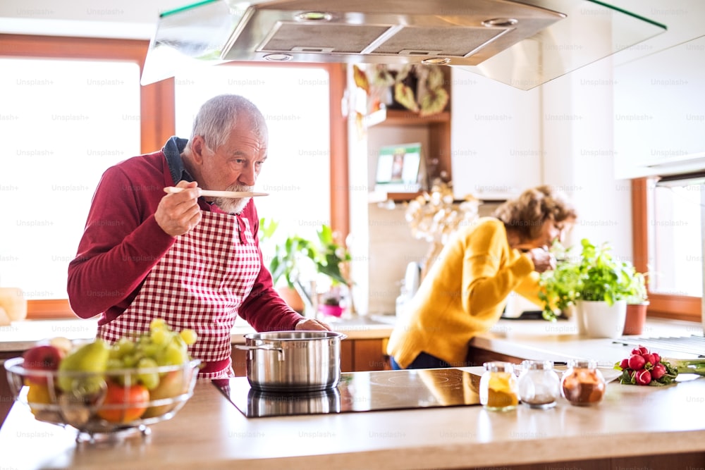 Älteres Ehepaar bereitet Essen in der Küche zu. Ein alter Mann und eine alte Frau im Haus.