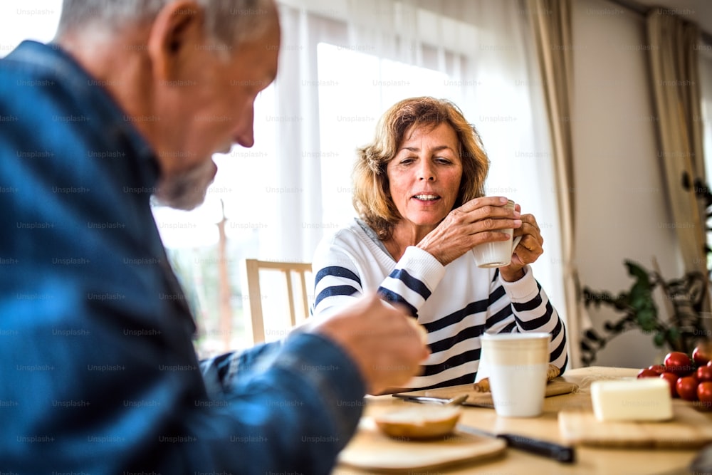 Senior couple eating breakfast at home. An old man and woman sitting at the table, eating breakfast.