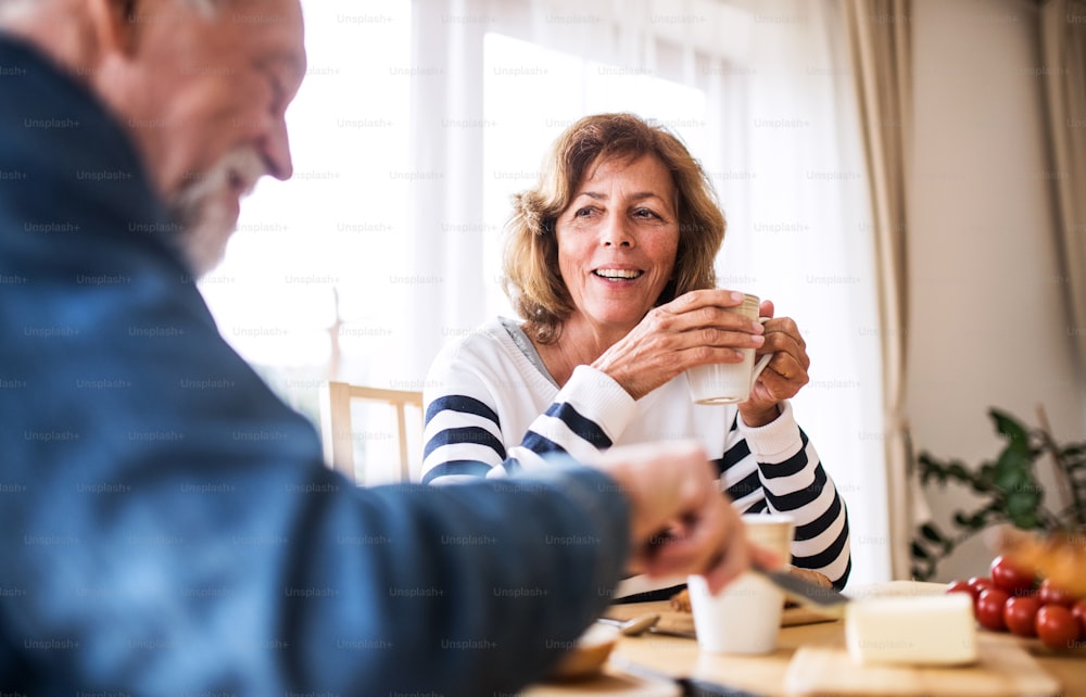 Senior couple eating breakfast at home. An old man and woman sitting at the table, eating breakfast.