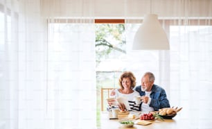 집에서 아침을 먹는 노부부. 늙은 남자와 여자가 테이블에 앉아 휴식을 취하고 있다.