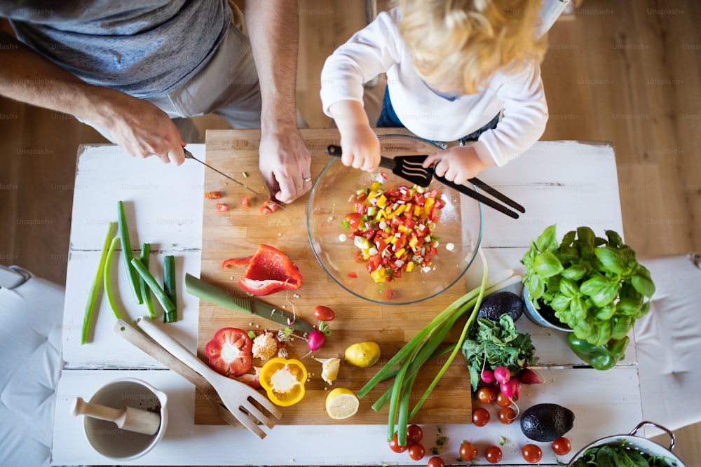 幼児の男の子が料理をしている認識できない父親。息子と野菜サラダを作る男。平面図。