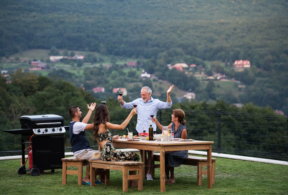 Retrato de pessoas com vinho ao ar livre no churrasco do jardim familiar, celebrando.
