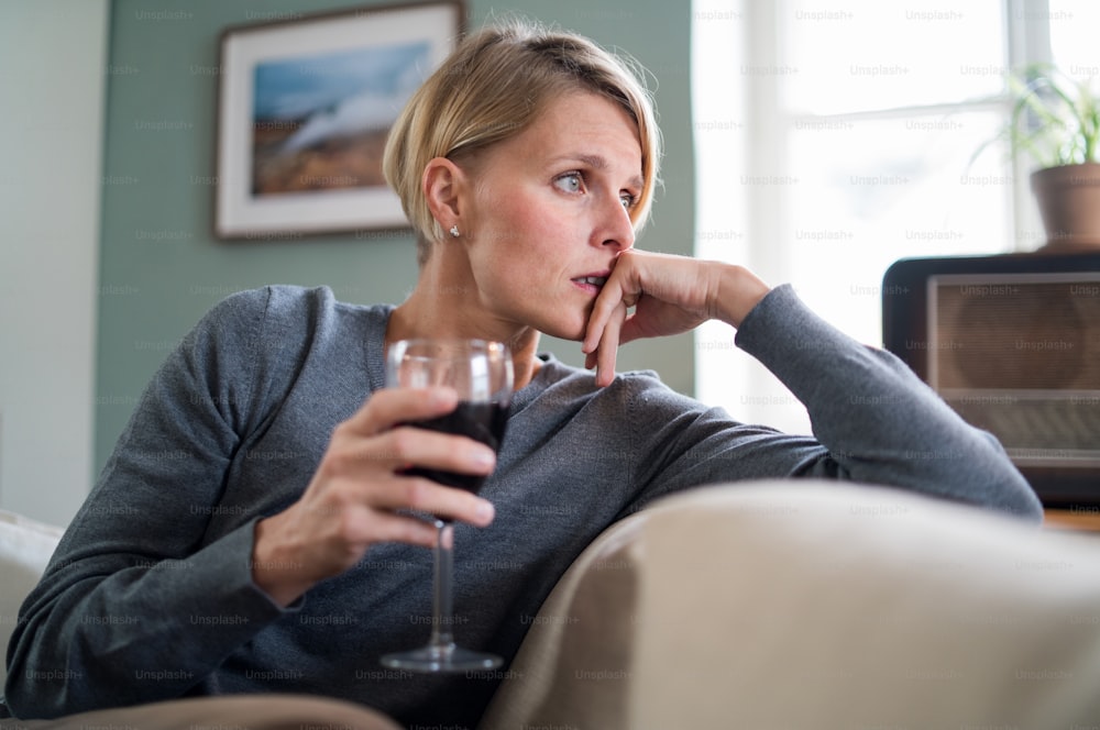 Donna depressa e sola con vino in casa a casa, concetto di salute mentale e dipendenza da alcol.