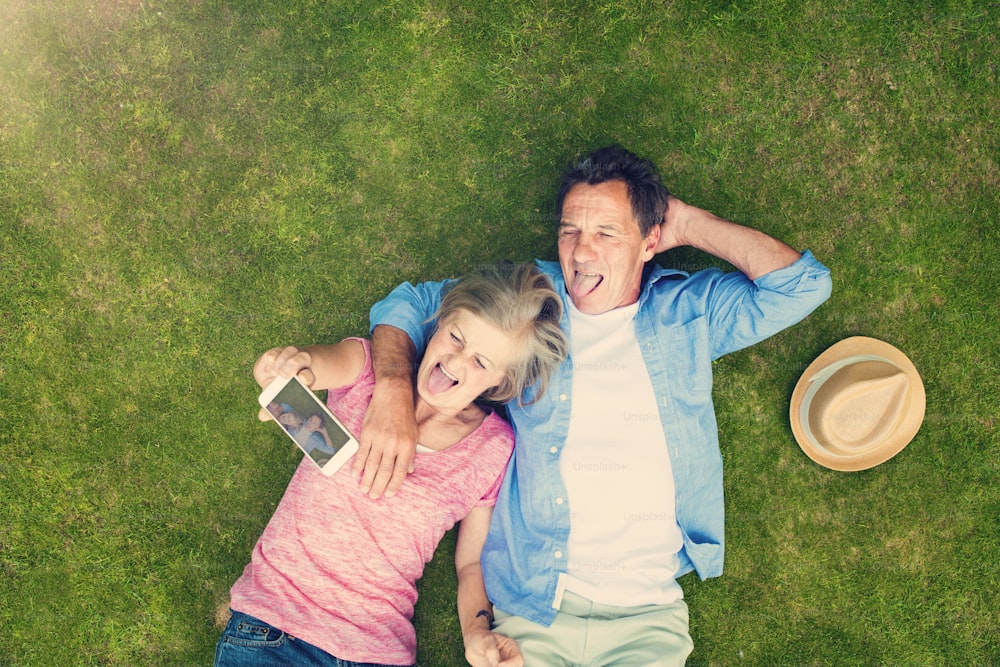 Beautiful seniors lying on a grass in a park hugging