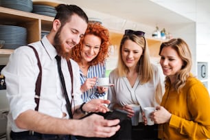 Un grupo de jóvenes empresarios alegres en la pausa para el café en la cocina de la oficina, tomándose selfie.