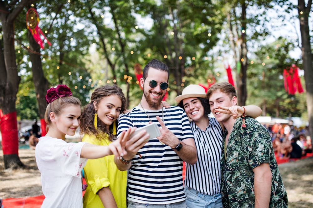 夏祭りでスマートフォンを持つ若い友人のグループの正面図、自分撮りをする。