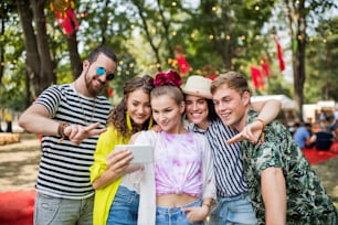 여름 축제에서 스마트폰을 들고 셀카를 찍는 젊은 친구들의 모습.