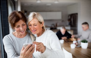 Un groupe d’amis seniors à la maison, utilisant des smartphones.
