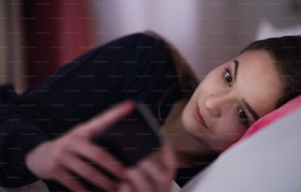 Une jeune fille utilisant un smartphone sur le lit, concept de rencontres en ligne.
