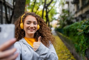 Portrait d’une jeune femme avec un smartphone à l’extérieur dans la rue, vidéo pour le concept de médias sociaux.