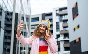 Portrait d’une jeune femme avec un smartphone réalisant des vidéos pour les médias sociaux en plein air dans la rue.