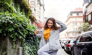 Retrato de mulher jovem com smartphone ao ar livre na rua, vídeo para conceito de mídia social.
