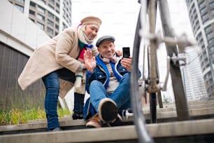 Ritratto di coppia anziana felice all'aperto sul marciapiede in città, scattando selfie.