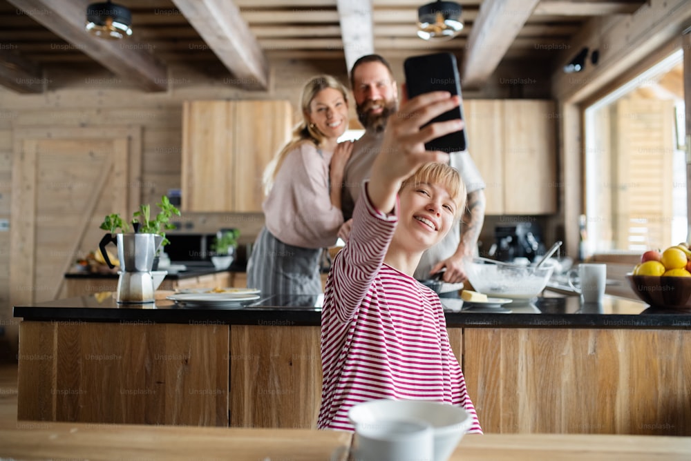 A family with small daughter taking selfie when cooking indoors, winter holiday in private apartment.